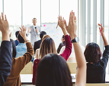 Group of business people raise hands up to agree with speaker in the meeting room seminar