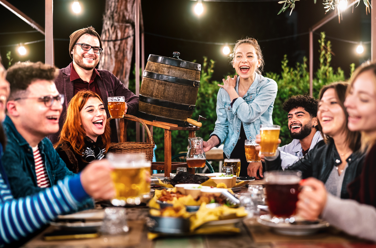 Happy men and women having fun drinking out at beer garden – Social gathering life style concept on young people enjoying hangout time together at night – Warm filter with shallow depth of field Quiz & Connect: Young Professional Networking and Trivia Night